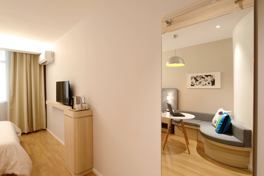Warm, tidy living room with a comfortable sofa and a bright hallway beyond